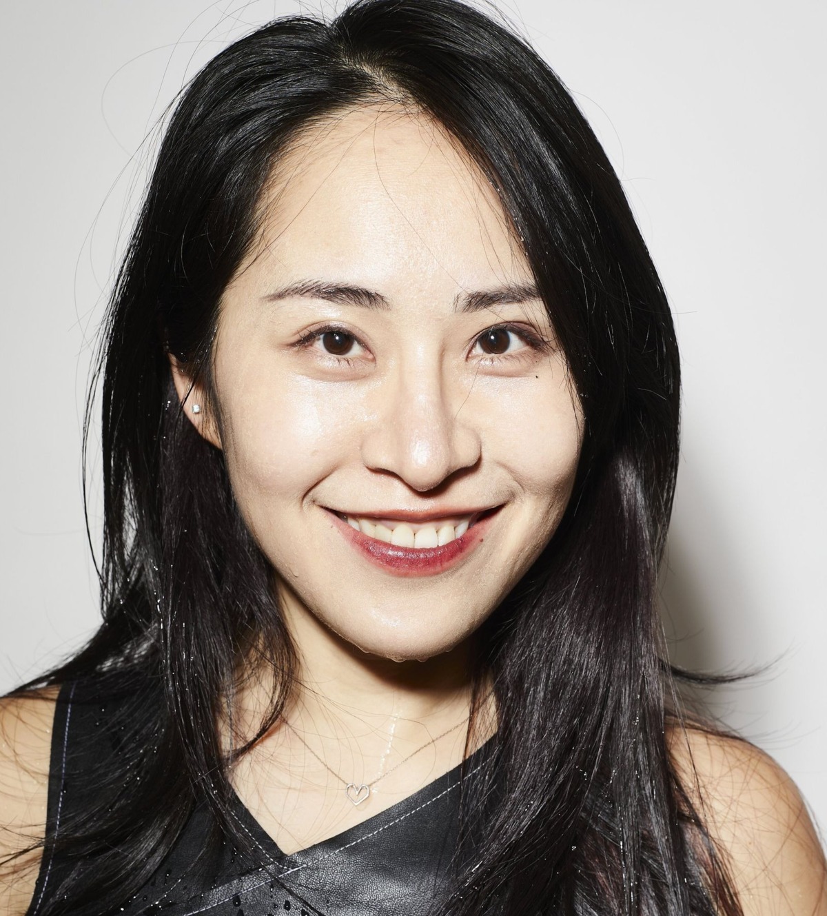 Porträt von Yi-Chen Tsai, die in einem schwarzen Kleid vor einem weissen Hintergrund sympathisch in die Kamera lacht.