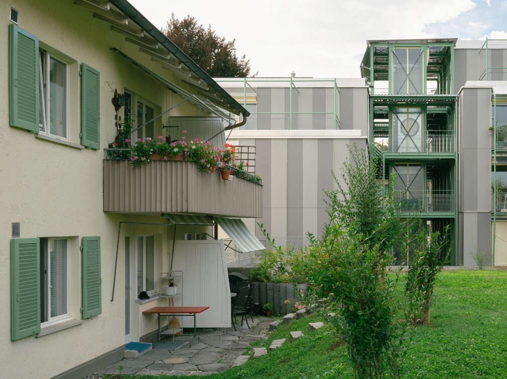 Sicht auf grünen Garten und Balkon mit Blumen einer Wohnung